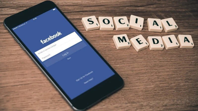 facebook app on smartphone and scrabble letters spelled to say social media
